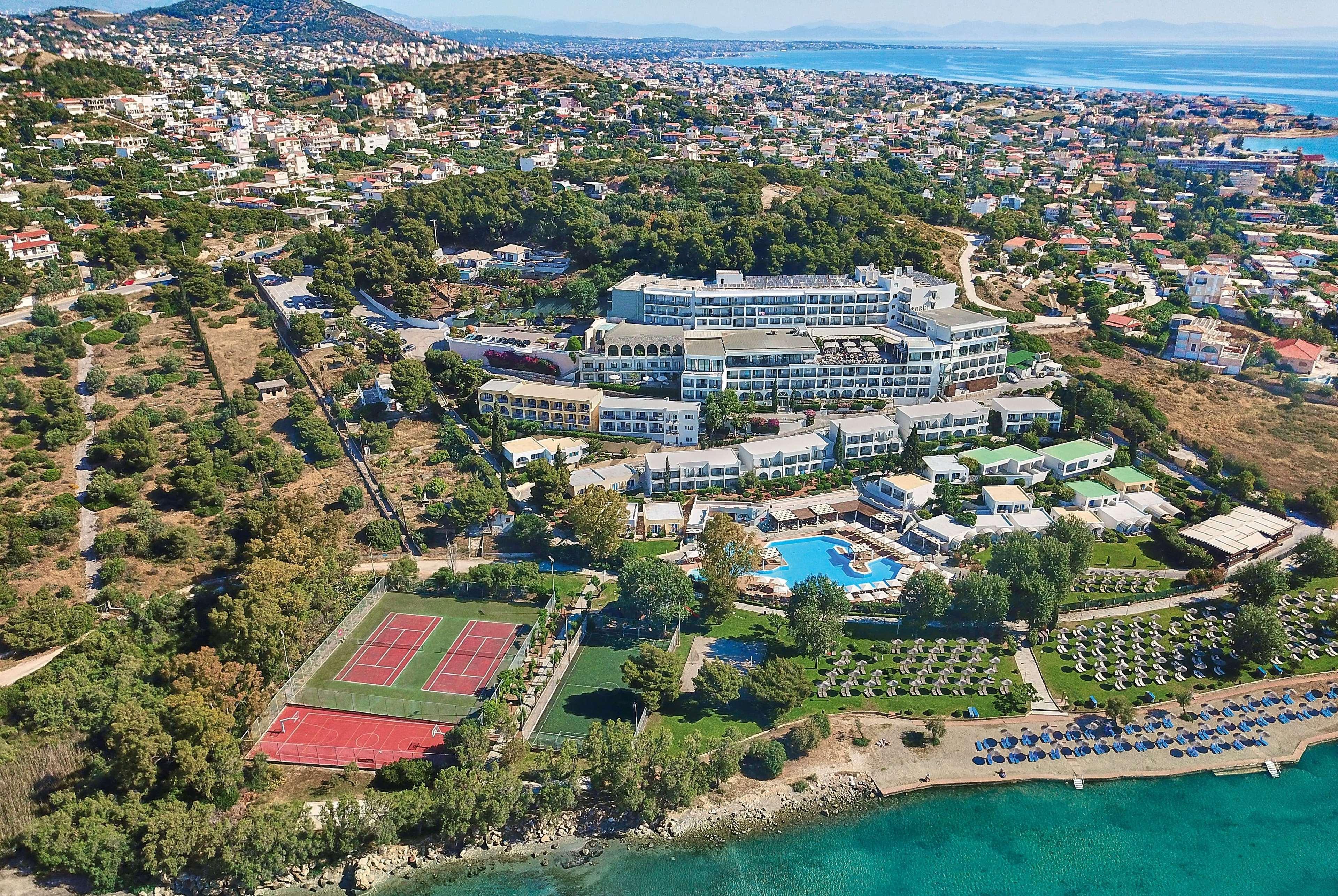 Dolce By Wyndham Athens Attica Riviera Hotel Vravrona Luaran gambar The photo shows an aerial view of a resort or hotel complex situated near the coast. The building appears to be large, with multiple levels and several balconies. Surrounding the hotel are green landscaped areas, including gardens and perhaps a pool.
