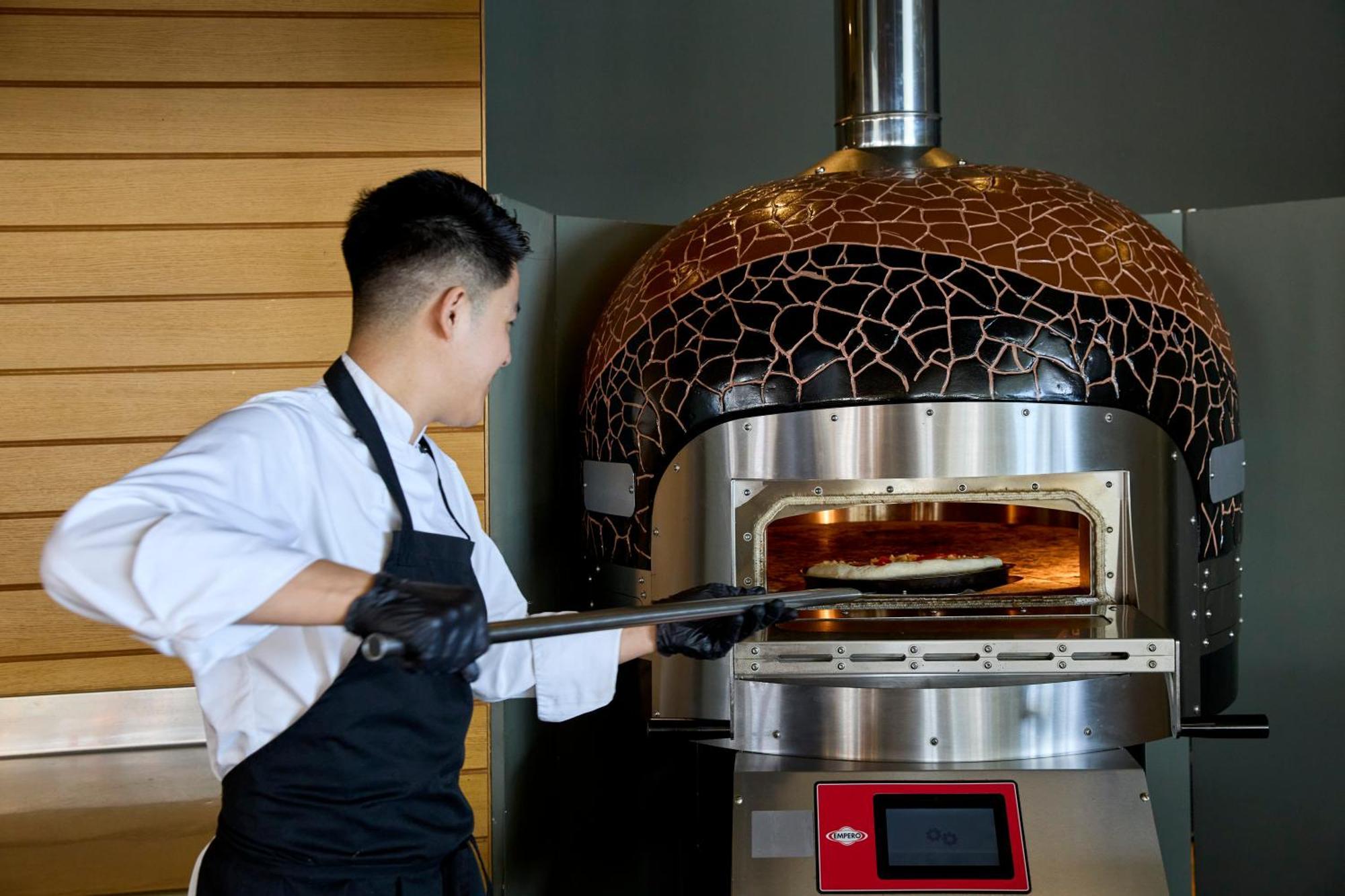 Dolce By Wyndham Athens Attica Riviera Hotel Vravrona Luaran gambar A pizzaiolo baking a pizza in a wood-fired oven